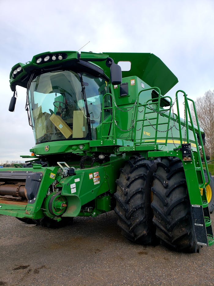 A detailed view of a green combine harvester parked outdoors on a farm.