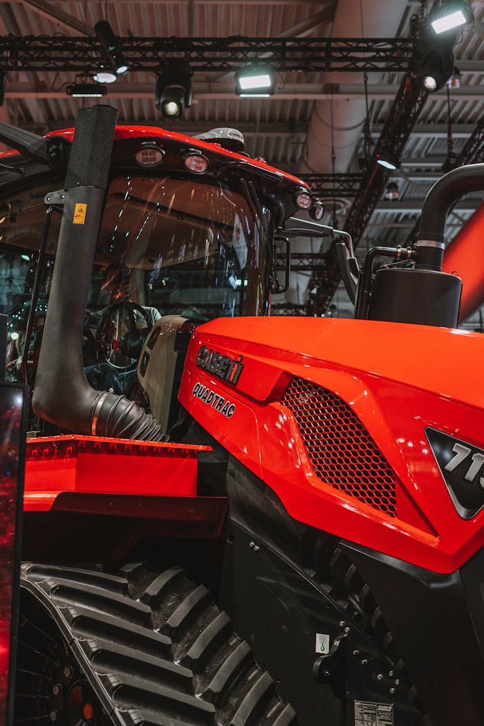Features Close-up of a red tractor displayed indoors at a machinery exhibition.