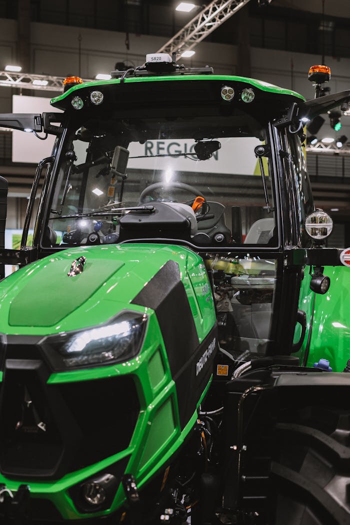 Features A close-up of a vibrant green tractor on display at an indoor exhibition.